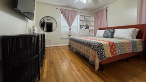 A bedroom with a bed, a TV, a ceiling fan, and a window with curtains. - Rice Village Retreat, World Cup 2026 (Houston)