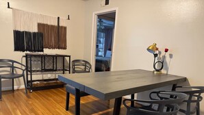 A dining area with a long table and chairs, a black metal frame, and a wooden floor. - Rice Village Retreat, World Cup 2026 (Houston)