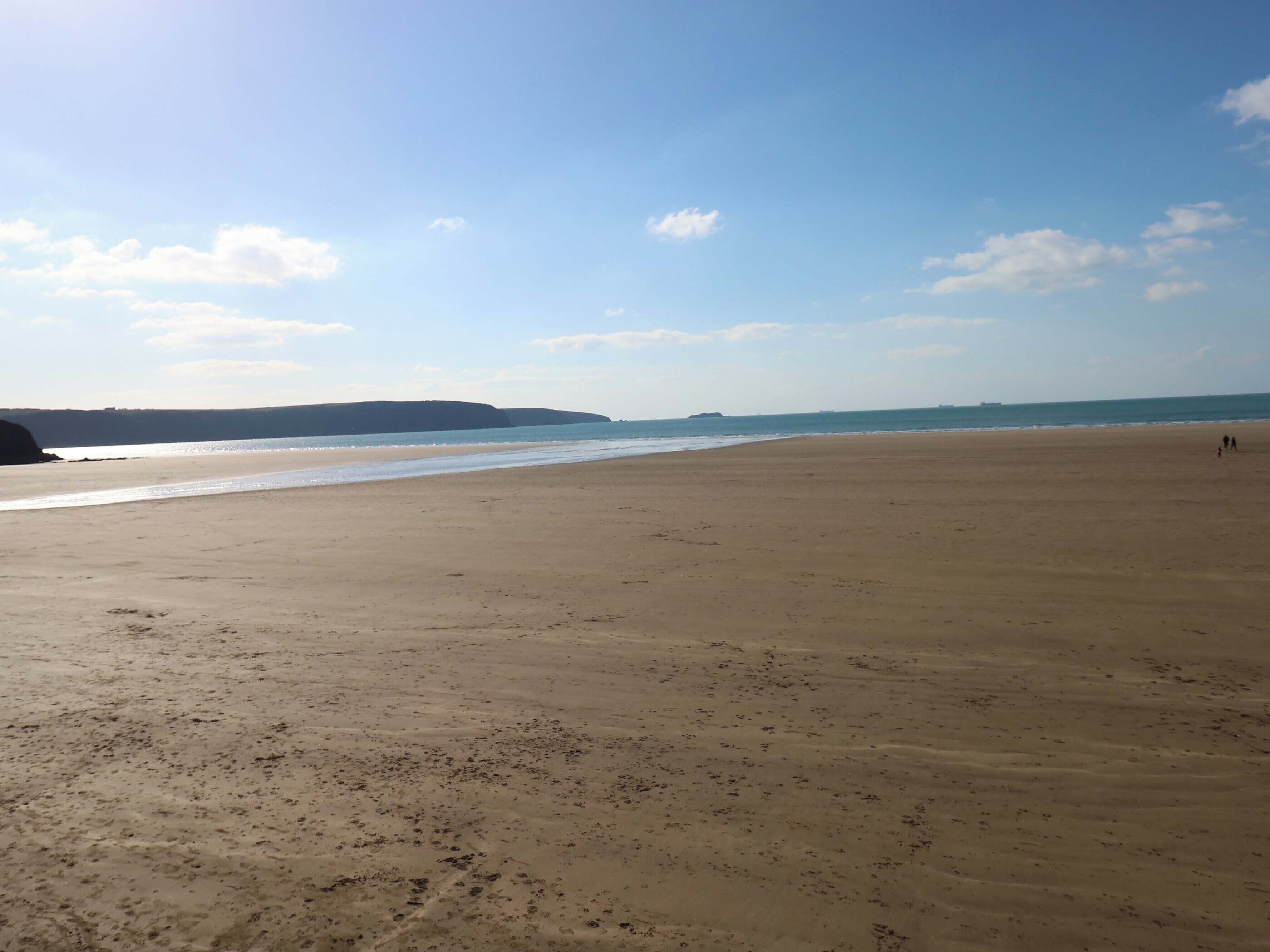 Une vaste plage de sable fin, avec des vagues douces et un ciel dégagé.