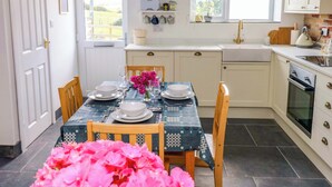 Une cuisine avec des meubles blancs, un évier et un coin repas avec une table mise pour deux personnes.