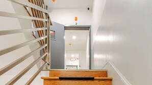 A wooden staircase with a metal railing and a black mat at the bottom.
