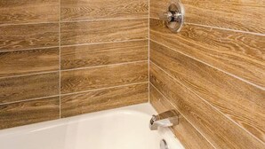 A modern bathroom with a freestanding bathtub, wooden wall tiles, and a chrome faucet.