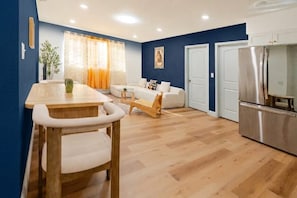 A modern kitchen with a dining area, a sofa, and a refrigerator.
