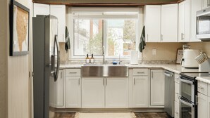 A kitchen with white cabinets, a stainless steel sink, a refrigerator, and an oven. - Pinch of Cozy ~ Hot Tub Theater ~ Seven Sons Farm (Roanoke)