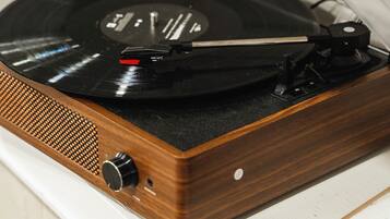 Une platine vinyle dotée d’un socle en bois et d’un couvercle transparent, posée sur une surface blanche.