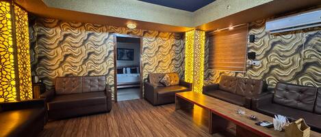 A modern lounge with a central seating area, wooden flooring, and patterned walls.