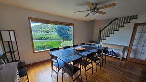 A dining area with a large window, a ceiling fan, and a staircase.