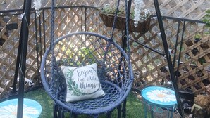 A garden area with a swing chair, two small tables, and a decorative pillow.