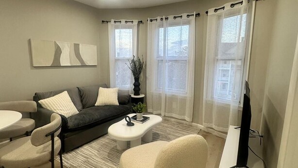 A modern living room with a sofa, armchairs, a coffee table, and a TV stand. - Cozy 2-bedroom apartment Near Six Flags & Attractions (Springfield)