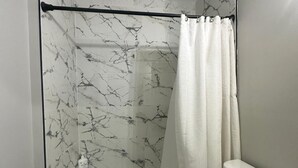 A bathroom with a bathtub, toilet, and a shower curtain. - Cozy 2-bedroom apartment Near Six Flags & Attractions (Springfield)