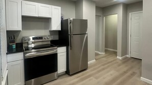 A modern kitchen with white cabinets, stainless steel appliances, and a light wood floor. - Cozy 2-bedroom apartment Near Six Flags & Attractions (Springfield)