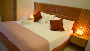 A neatly made bed with a wooden headboard, a pink bedspread, and two bedside lamps.