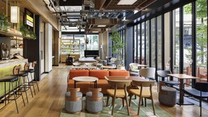 Ett modernt café med en bardisk i trä, orangea sittplatser och stora fönster med utsikt över gatan.