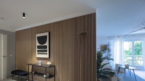 A modern living room with a striped wall, a black-framed picture, a small table with a chair, and a large window with a view of greenery. - LE ROSSINI Antibes Center, AirCo, Parking for 4 By Sunset (Antibes)