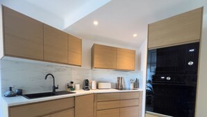 A modern kitchen with wooden cabinets, a marble countertop, and a black appliance. - LE ROSSINI Antibes Center, AirCo, Parking for 4 By Sunset (Antibes)