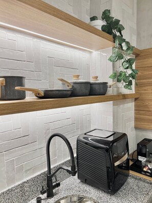 A kitchen with white brick backsplash, wooden shelves, a plant, and a portable kitchen setup. - AD 330 (São Paulo)