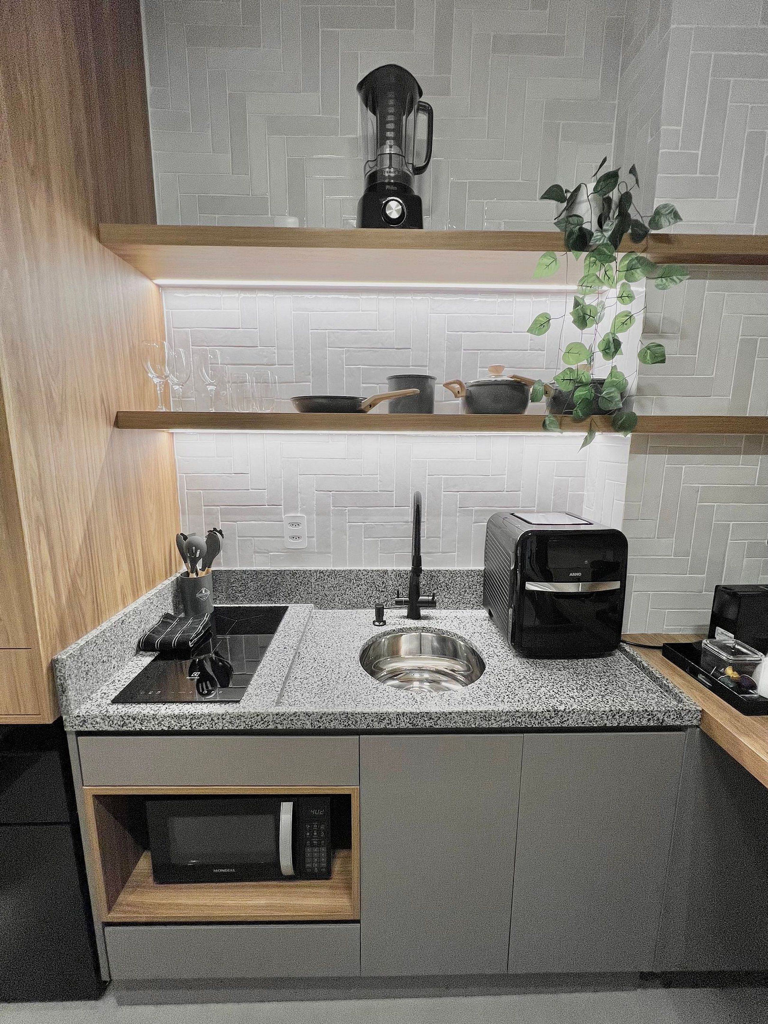A modern kitchen with a granite countertop, stainless steel sink, a toaster, a blender, and a microwave.