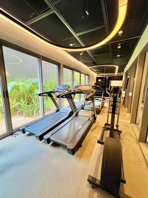 A gym with treadmills and exercise equipment, large windows with a view of greenery, and a modern ceiling design. - AD 330 (São Paulo)