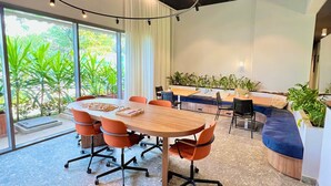 A modern meeting room with a large oval table, orange chairs, and a blue sofa. - AD 330 (São Paulo)
