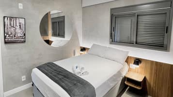 Un dormitorio moderno con cama, mesitas de noche, un espejo y una ventana con persianas.