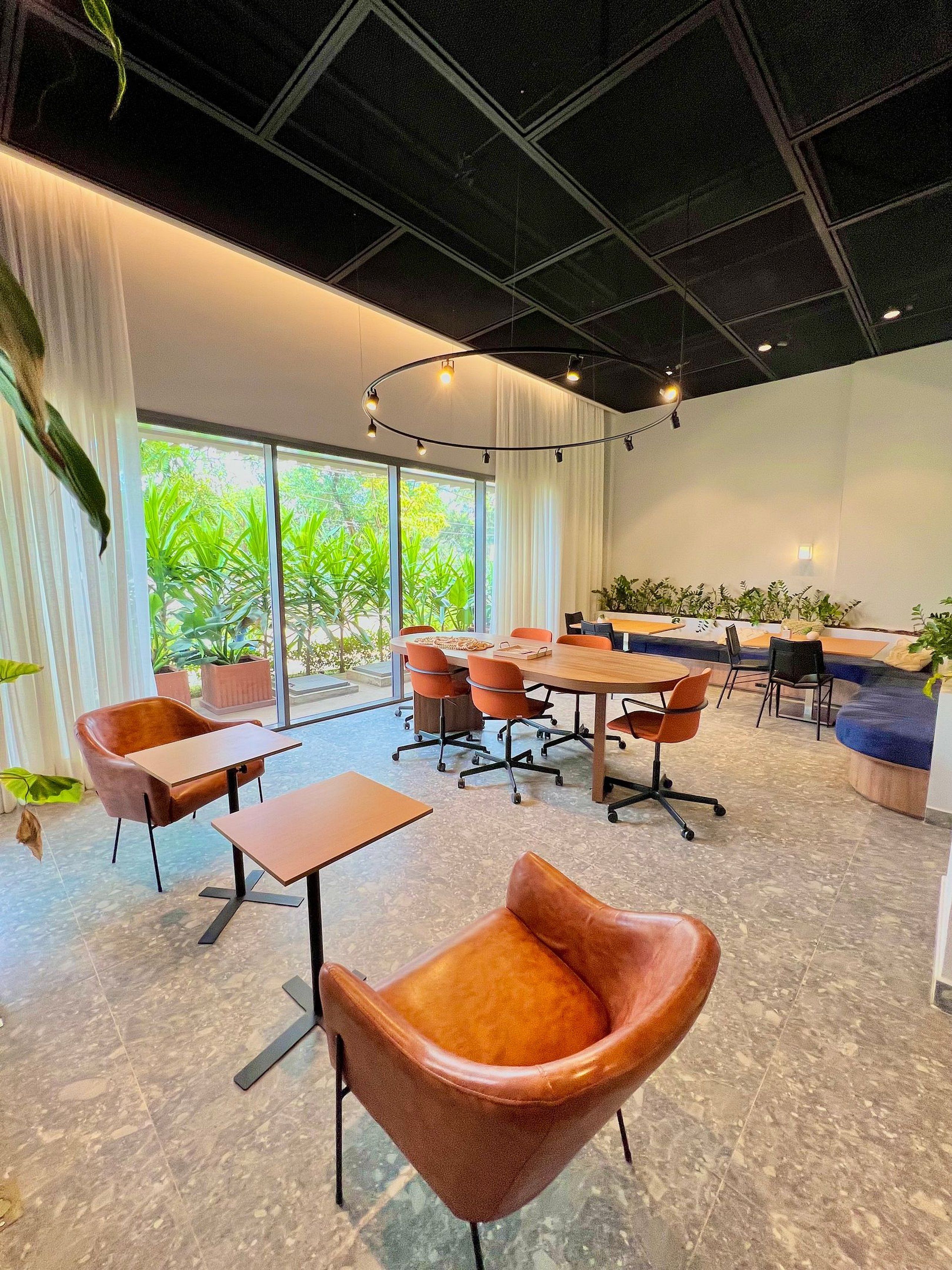 Une salle de conférence moderne, dotée d’une grande table, de fauteuils en cuir et de plantes en pot.