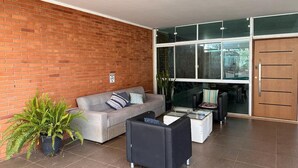 Un saló modern amb una paret de maó, un sofà gris, un butac armchair negre i una taula de centre de vidre.