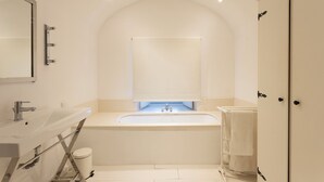 Un baño moderno con una bañera independiente, un espejo grande y un perchero para toallas.
