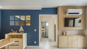 Une cuisine moderne dotée d’une cuisinière intégrée, un coin repas avec une table et des chaises, et un couloir menant à une salle de bain.