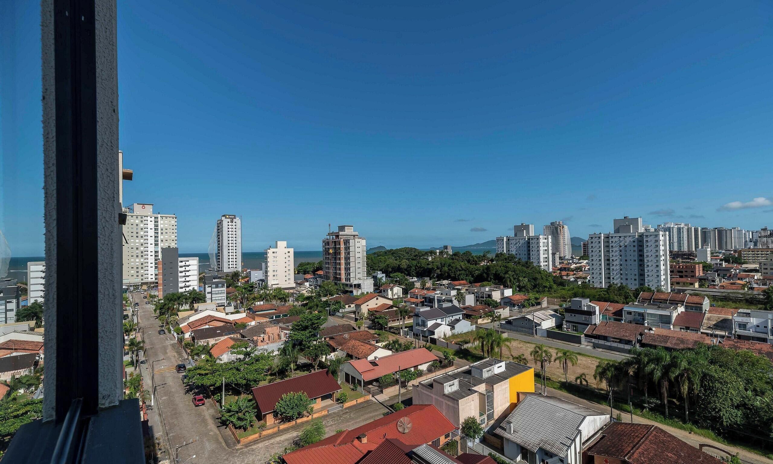 A cityscape with high-rise buildings, a clear sky, and a view of the sea.