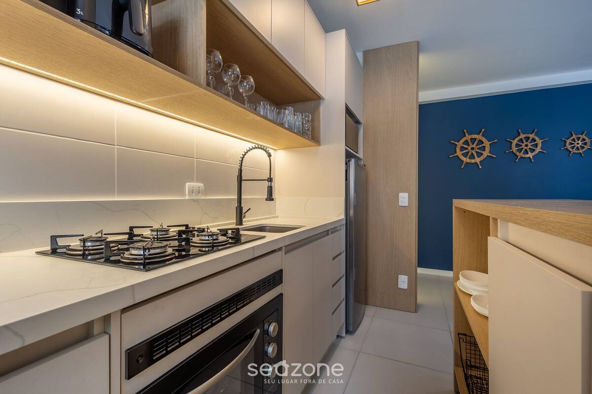 A modern kitchen with a gas stove, stainless steel appliances, and wooden shelves.