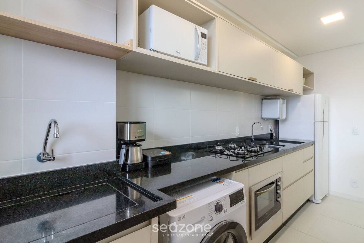 A modern kitchen with a built-in washing machine, a coffee maker, and a microwave.