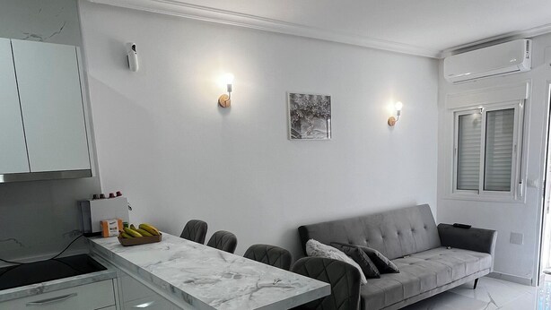 A modern kitchen with a marble countertop, a grey sofa, and a bar stool.