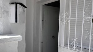 A hallway with a white door, a metal gate, and a welcome mat.