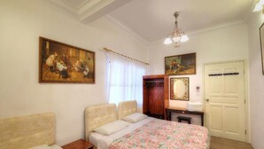 A bedroom with a bed, two bedside tables, a wooden wardrobe, a mirror, and two paintings on the wall. - Cozy 10-bedroom bungalow in Cameron Highlands (Tanah Rata)