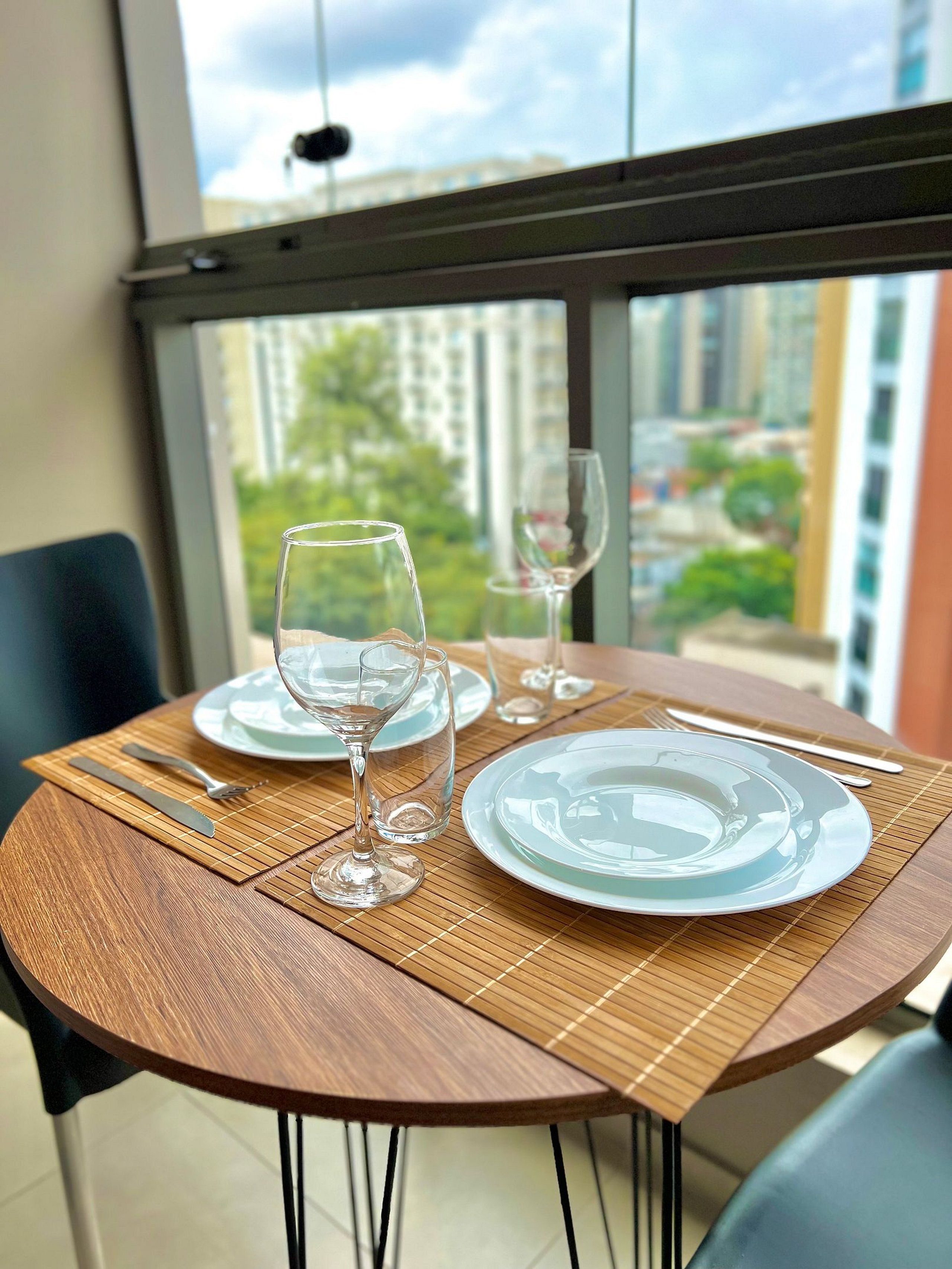 Een eettafel met borden, bestek en glazen op een bamboe onderzetter.