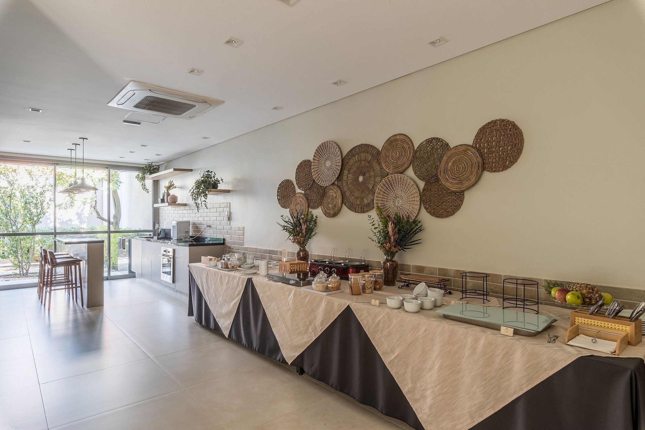Cozinha moderna com bancada comprida, área de jantar com cadeiras e parede decorada com cestos de palha.