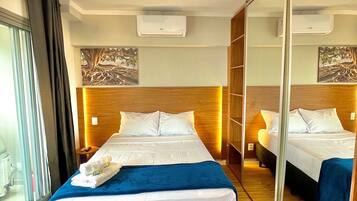 A hotel room with a large bed, a mirror, and a view of the outside.