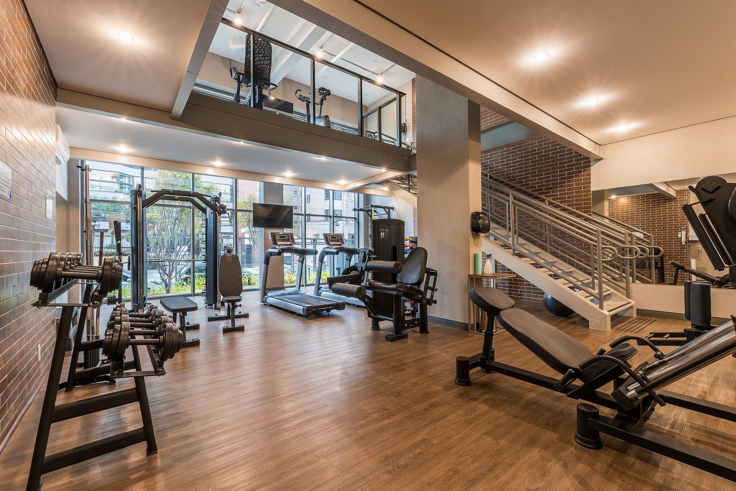 Ein Fitnessraum mit Laufbändern, Kraftgeräten und einer Treppe.