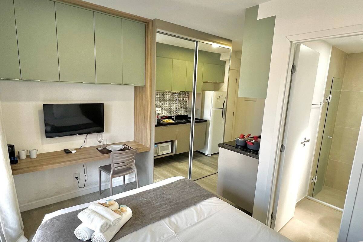 Une chambre d’hôtel moderne équipée d’un lit, d’une télévision, d’un bureau et d’une kitchenette.