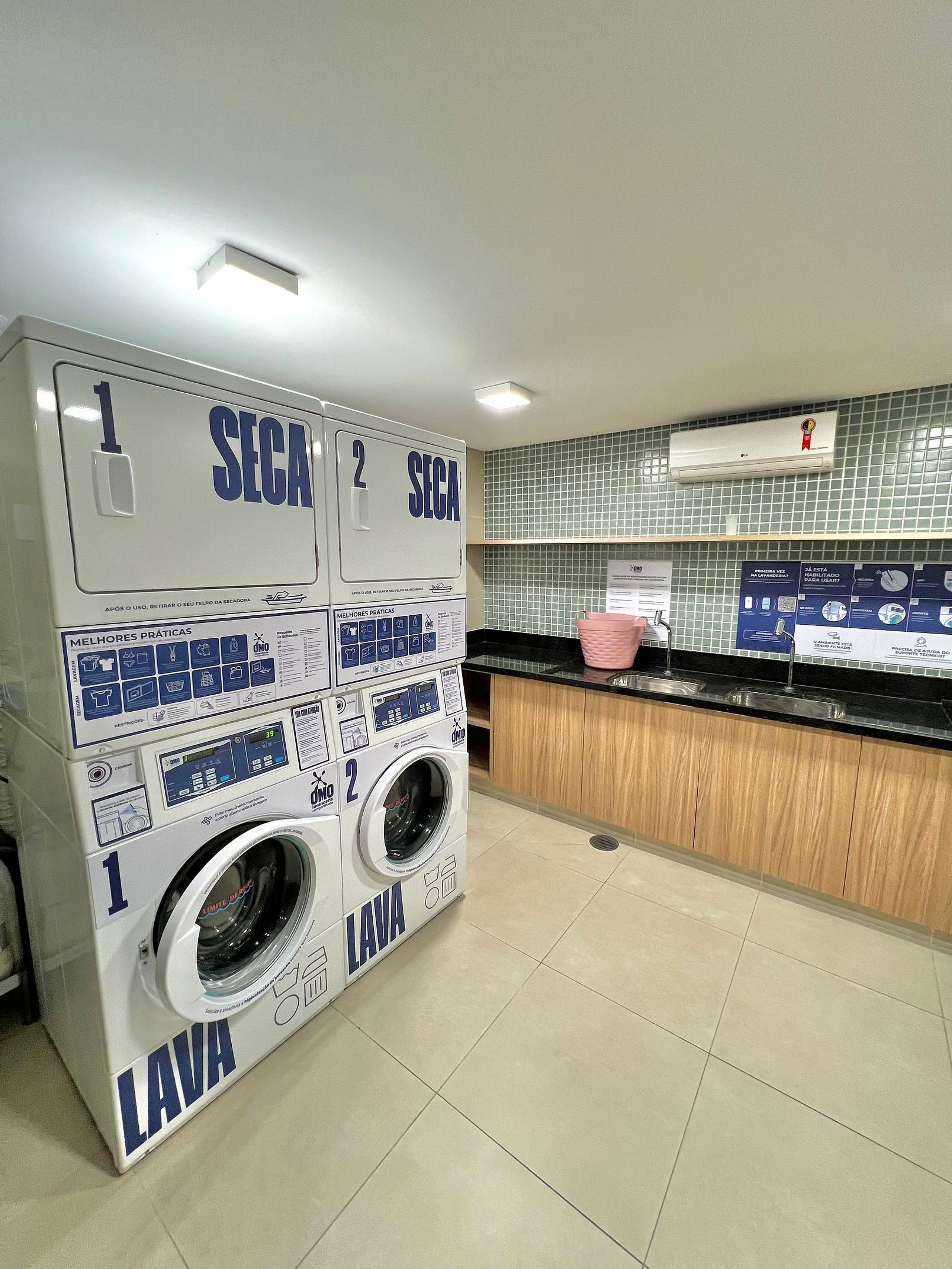 A laundry facility with two washing machines, a sink, and a tiled backsplash.