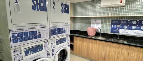 A laundry facility with two washing machines, a sink, and a tiled backsplash.