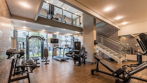 Un gimnasio con cintas de correr, máquinas de pesas y una escalera.