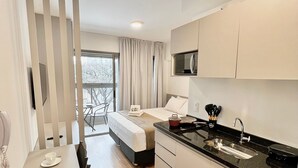 Una cocina moderna con encimera negra, armarios blancos y un comedor con mesa y sillas.