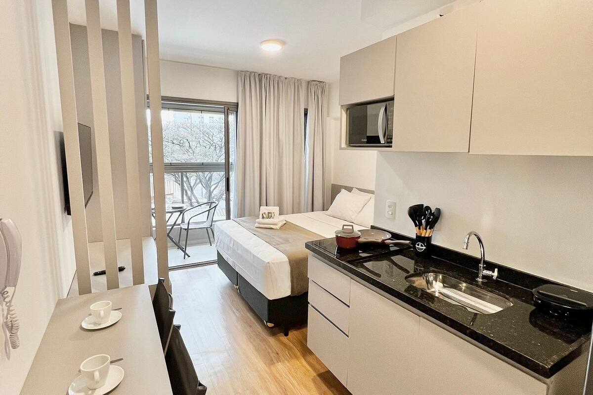 Une cuisine moderne avec un plan de travail noir, des meubles blancs et un coin repas comprenant une table et des chaises.