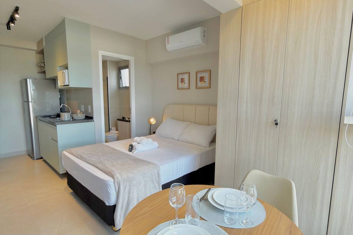 Une chambre d’hôtel moderne équipée d’un lit, d’une table de chevet et d’un coin repas avec une table mise pour deux personnes.