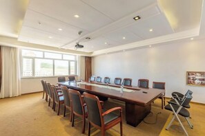 Una sala de conferencias con una larga mesa, sillas, un proyector y un amplio ventanal.