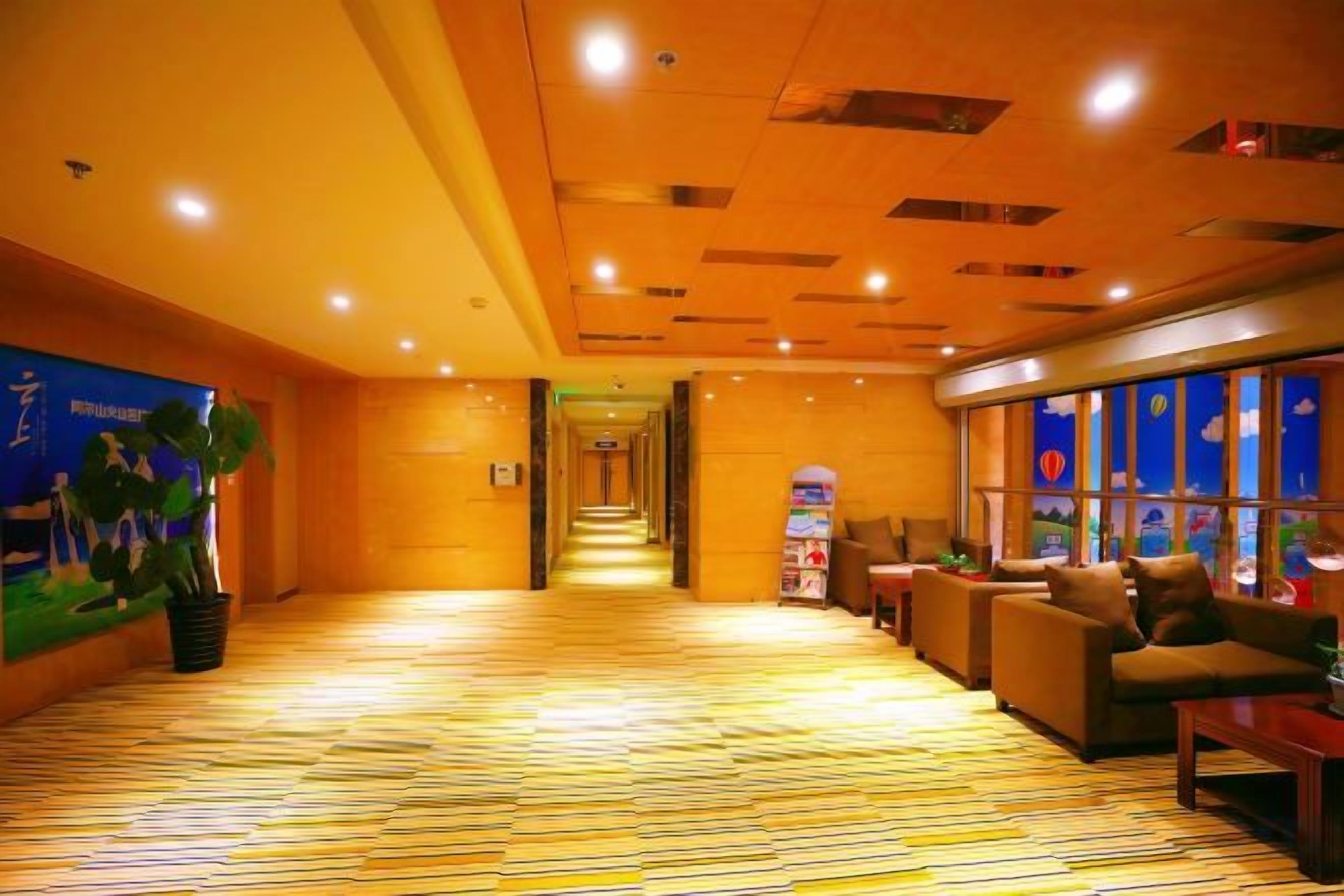 A hotel lobby with a long corridor, seating area, and a vending machine.