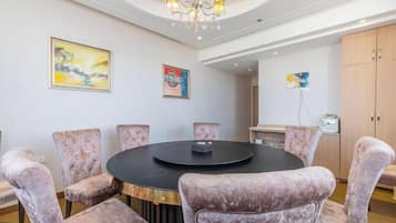 A conference room with a round table, six upholstered chairs, and a chandelier.