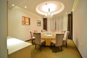 Comedor con una mesa redonda, sillas, candelabro y cortinas.