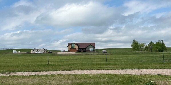 A rural property with a large house, a barn, and several trailers.